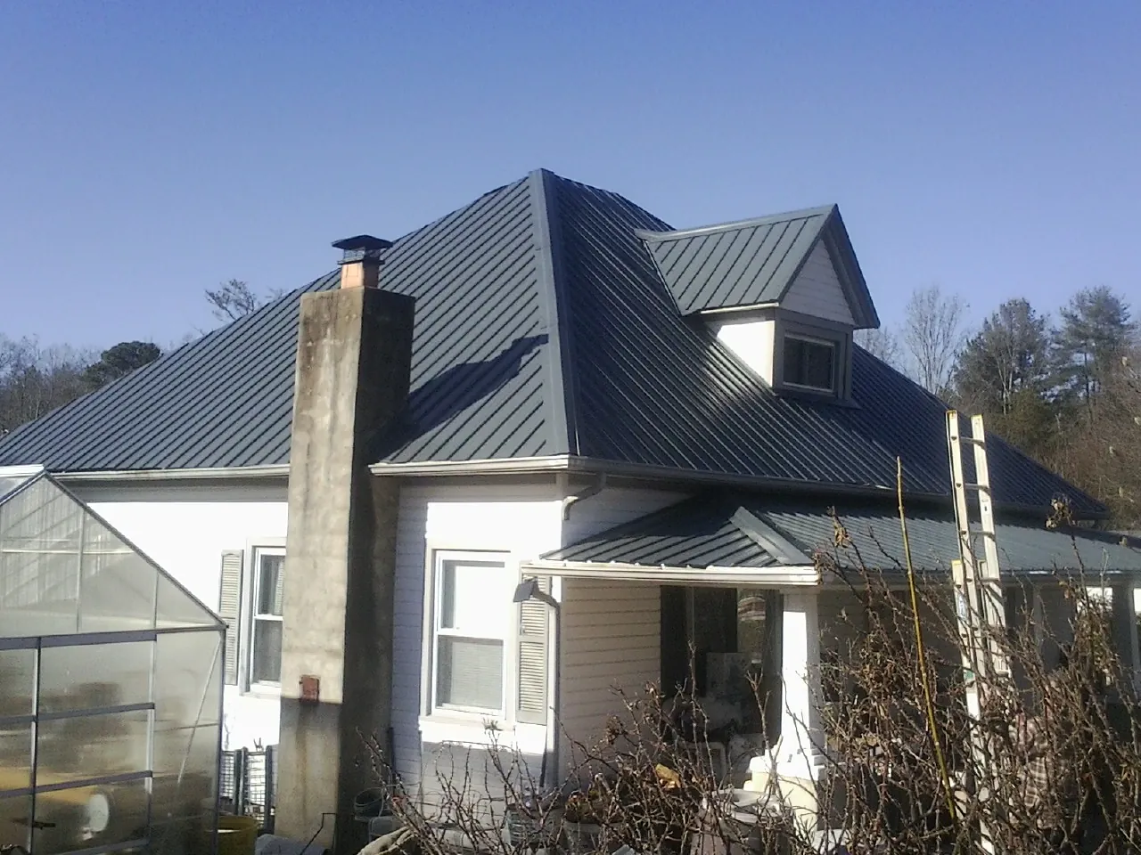 Dark blue standing seam metal roof on a white farmhouse with dormer — Slate & Tile Roof Repair by Roofing Brothers in Inglis