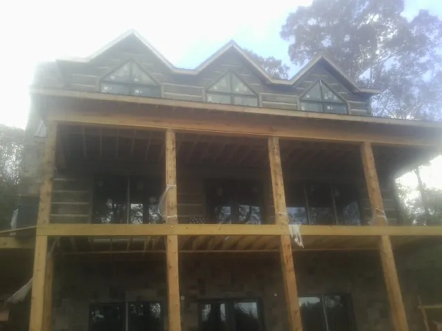 Dormers and porch framing on a large log home under construction — Roof Coating work by our crew in Inglis