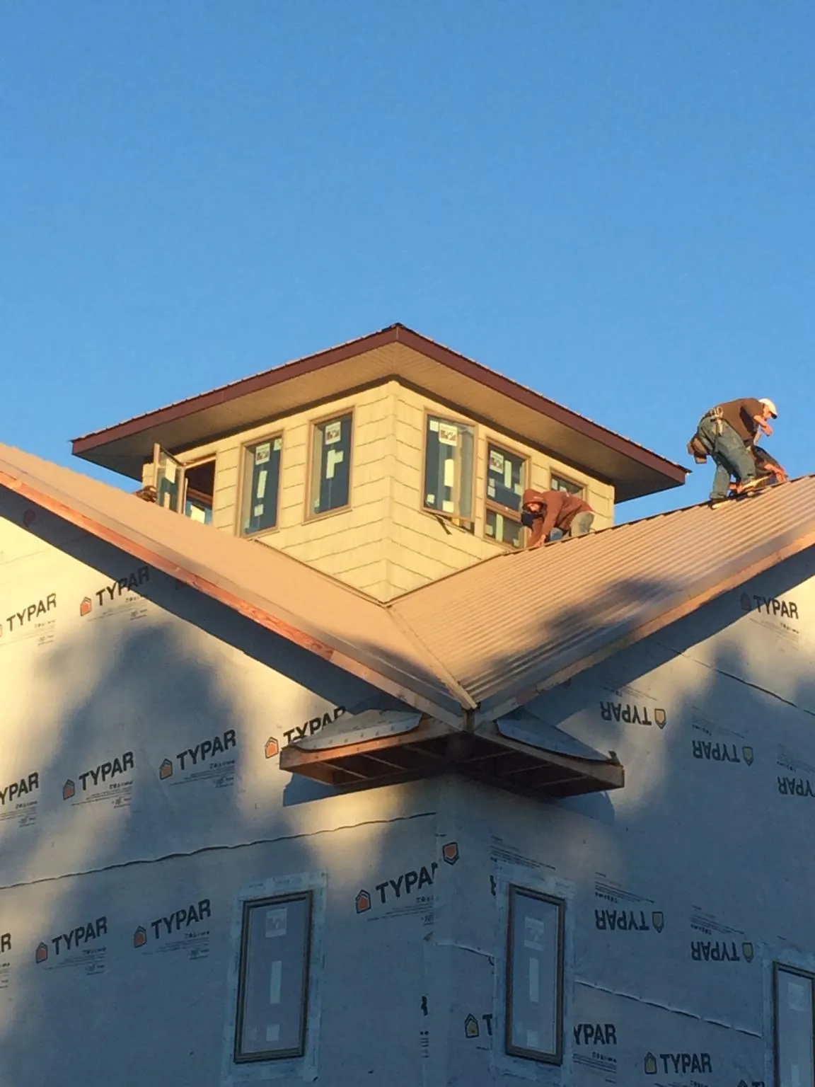 Roofers working around a rooftop cupola on a new metal roof at sunset — Roof Waterproofing in Inglis by Roofing Brothers
